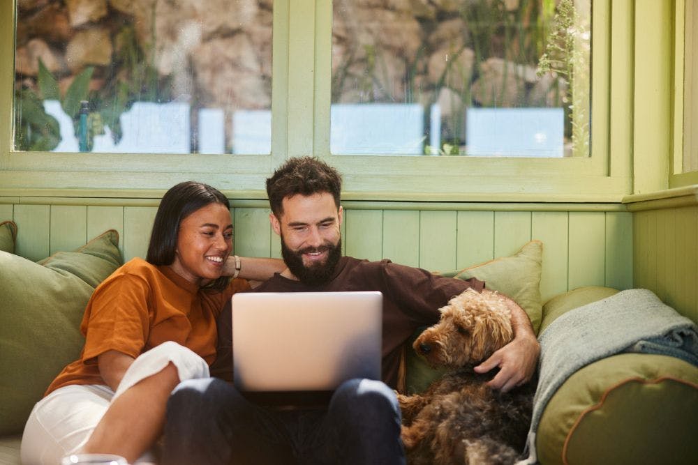 Regional Australia Bank Internet Banking designed around you | Young couple with a pet dog smiling at a laptop
